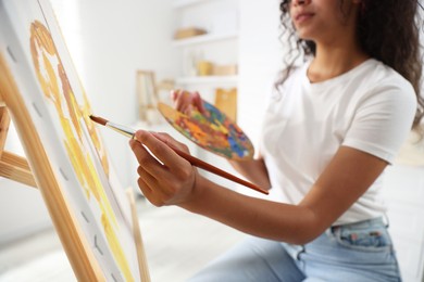 Photo of Woman drawing picture with paint in studio, closeup