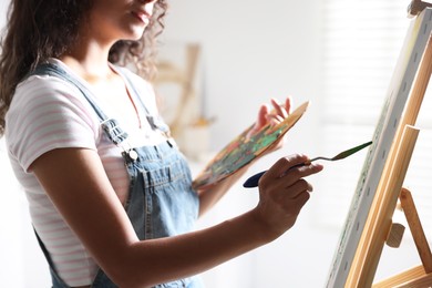 Photo of Woman drawing picture with palette knife in studio, closeup