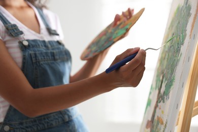 Woman drawing picture with palette knife in studio, closeup