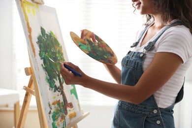 Photo of Woman drawing picture with palette knife in studio, closeup