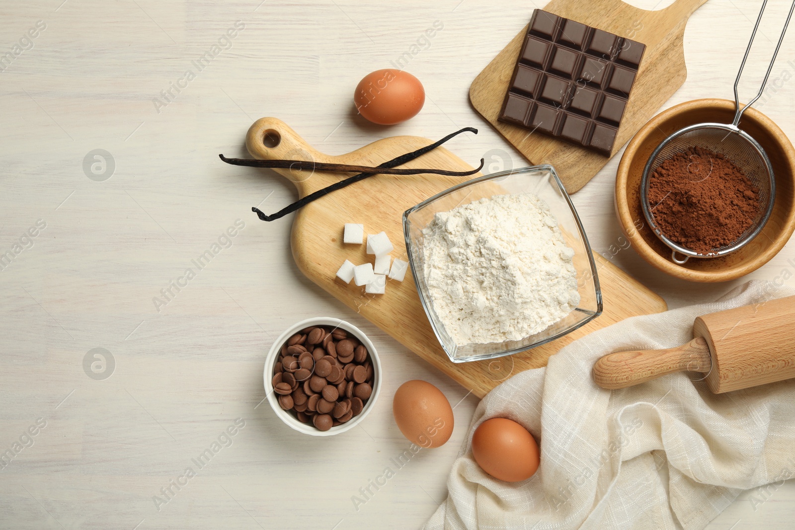 Photo of Flat lay composition with flour, eggs and other ingredients for making dough on light wooden table. Space for text