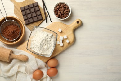 Photo of Flat lay composition with flour, eggs and other ingredients for making dough on light wooden table. Space for text