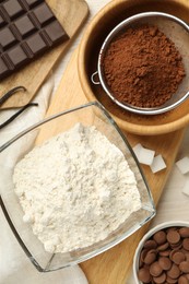 Photo of Flat lay composition with flour, chocolate and other ingredients for making dough on light table