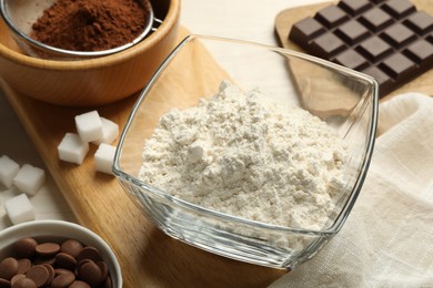 Photo of Flour in bowl and chocolate for making dough on light table, closeup