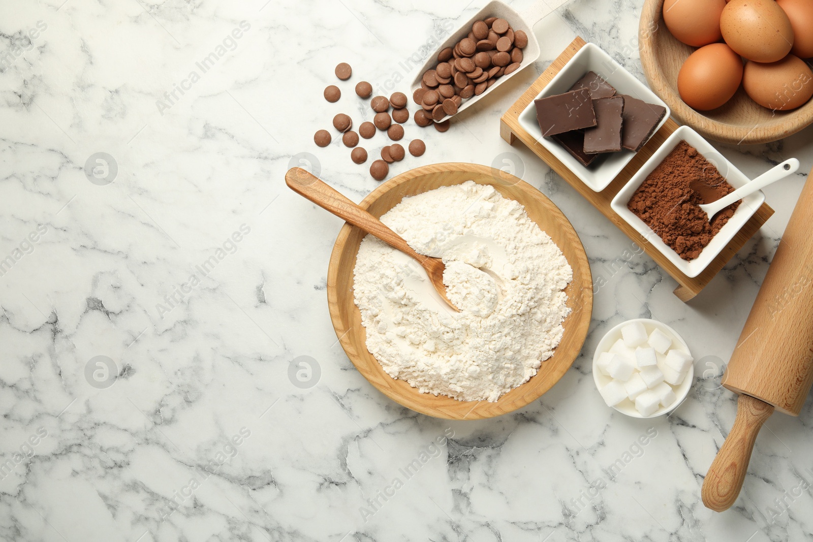 Photo of Flat lay composition with flour, chocolate and other ingredients for making dough on white marble table. Space for text