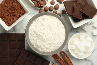 Photo of Flat lay composition with flour, chocolate and other ingredients for making dough on white marble table