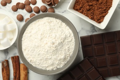 Photo of Flat lay composition with flour, chocolate and other ingredients for making dough on white marble table