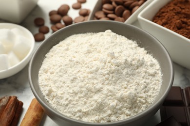 Photo of Flour in bowl and chocolate for making dough on white table, closeup