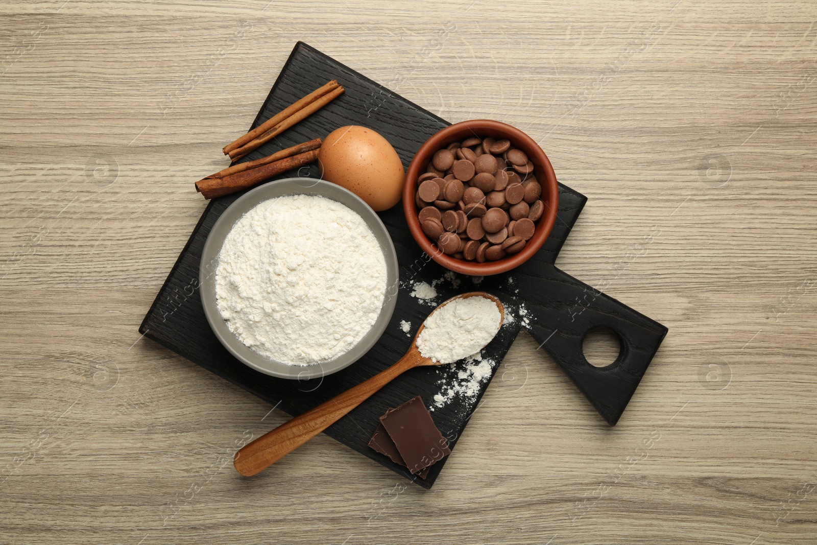 Photo of Flour, chocolate and other ingredients for making dough on wooden table, top view