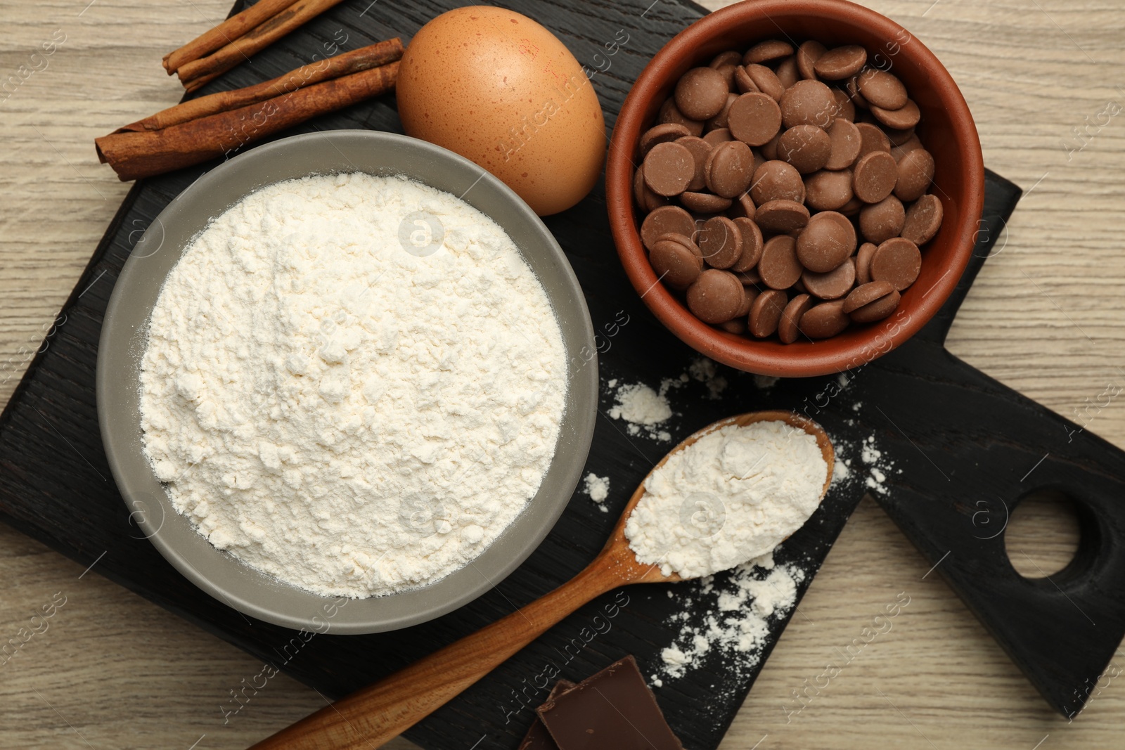 Photo of Flour, chocolate and other ingredients for making dough on wooden table, top view