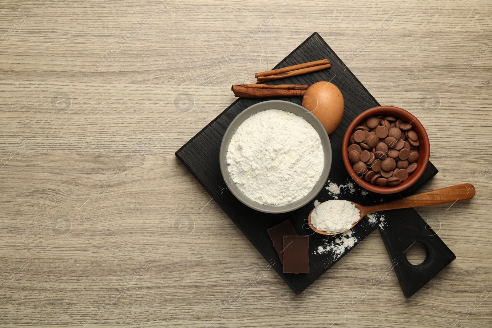 Photo of Flour, chocolate and other ingredients for making dough on wooden table, top view. Space for text