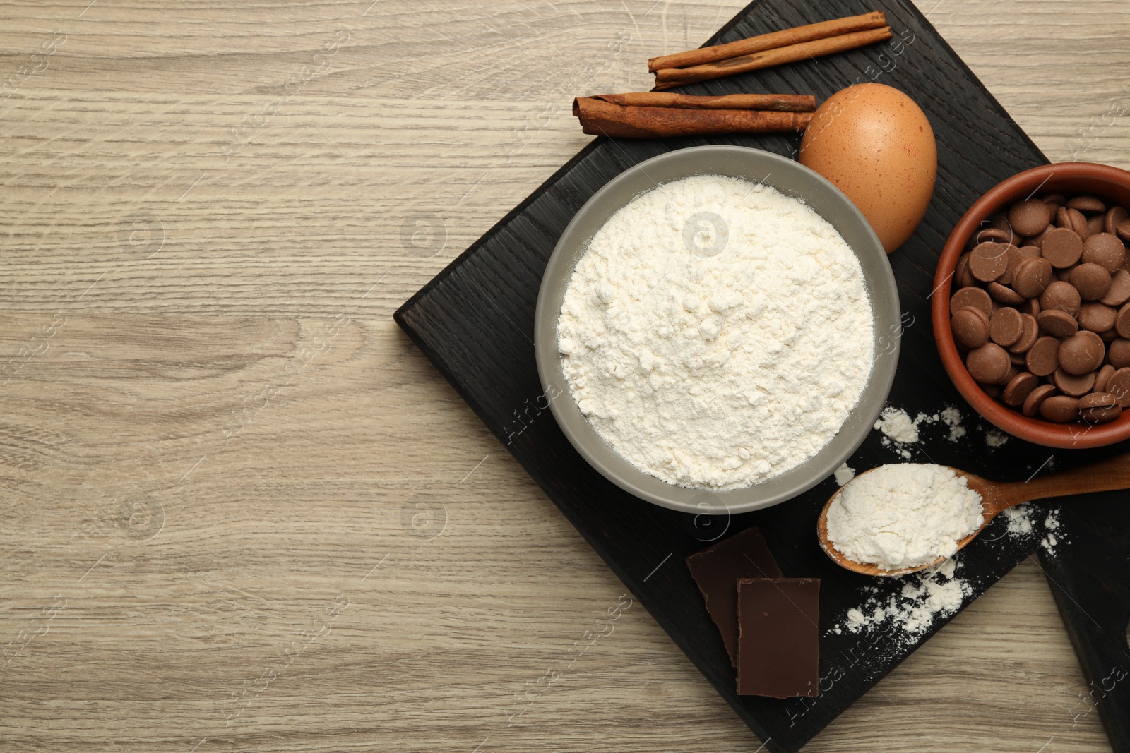 Photo of Flour, chocolate and other ingredients for making dough on wooden table, top view. Space for text