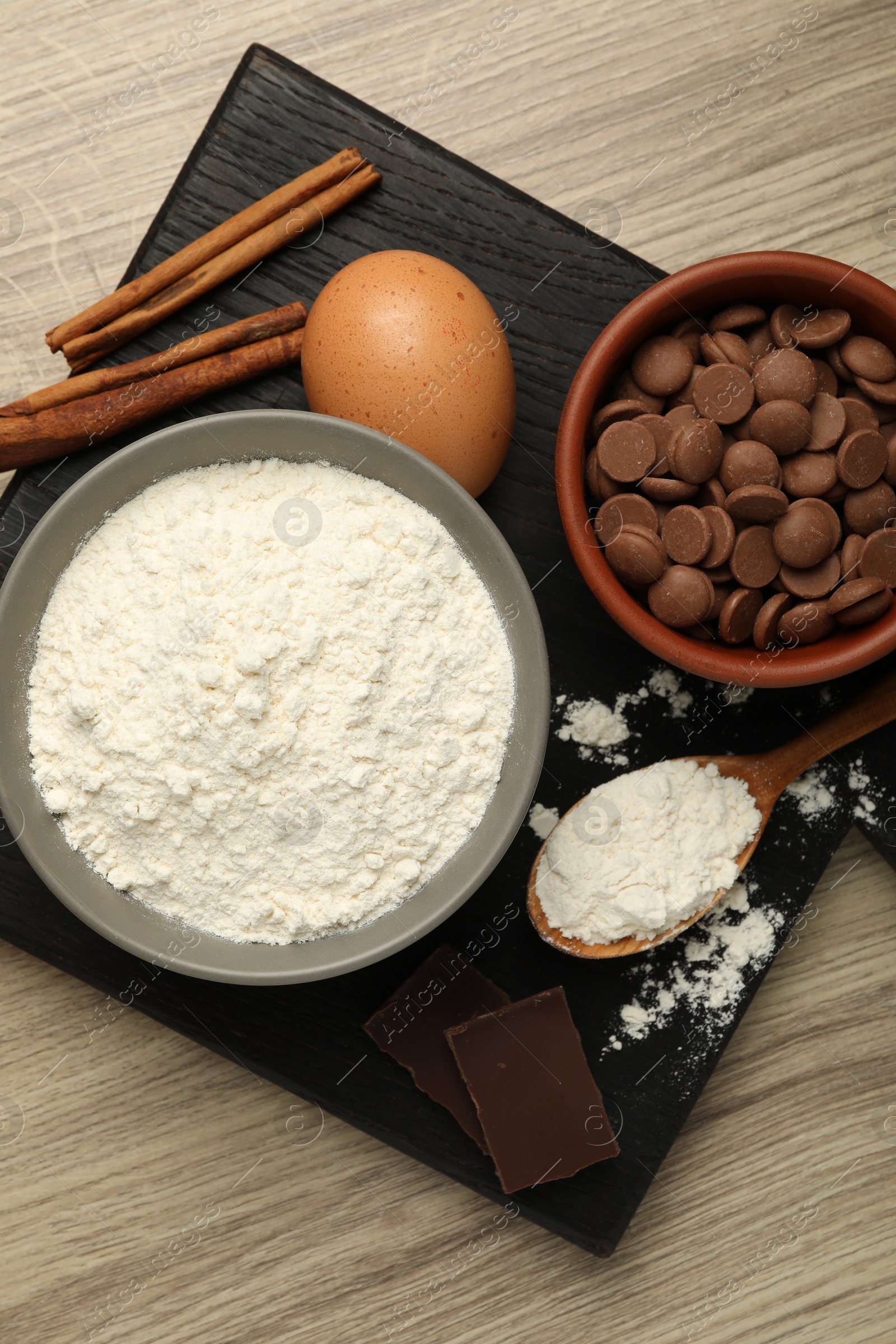 Photo of Flour, chocolate and other ingredients for making dough on wooden table, top view