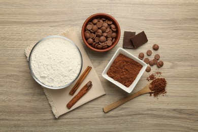 Photo of Flour, chocolate and cocoa for making dough on wooden table, flat lay