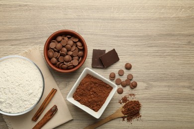 Photo of Flour, chocolate and cocoa for making dough on wooden table, flat lay. Space for text