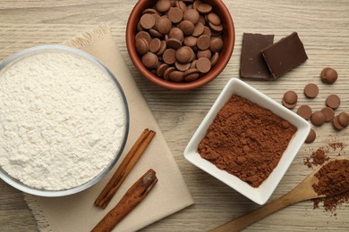 Photo of Flour, chocolate and cocoa for making dough on wooden table, flat lay