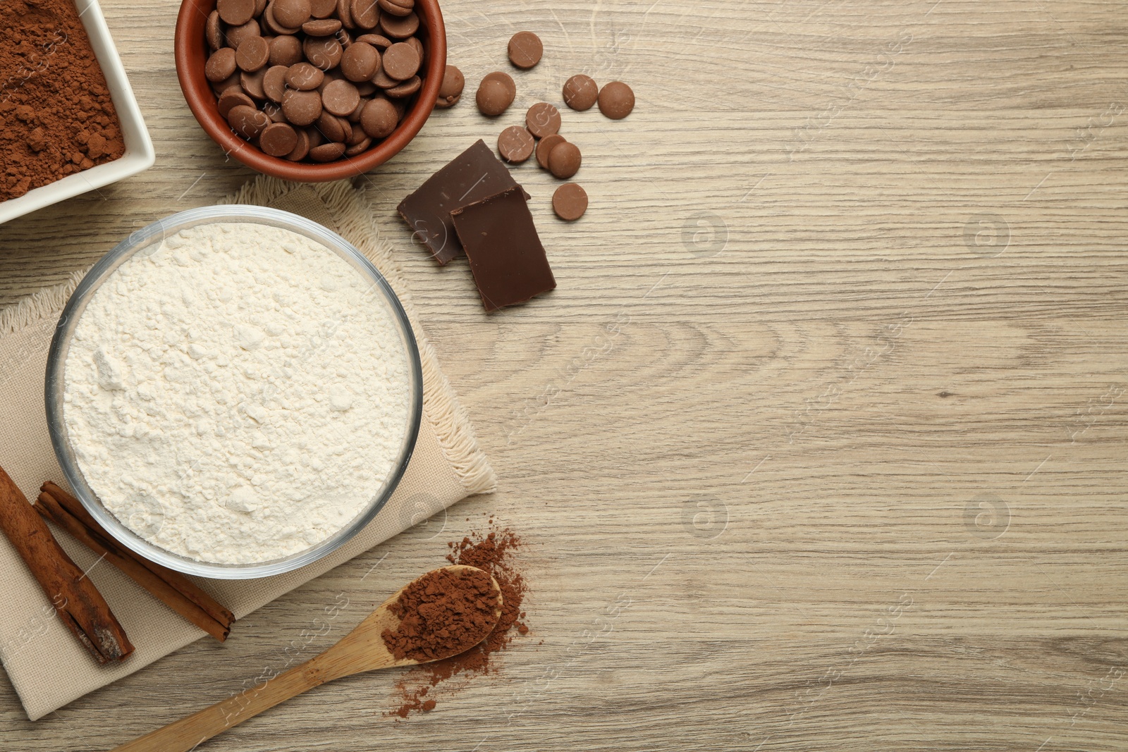 Photo of Flour, chocolate and cocoa for making dough on wooden table, flat lay. Space for text