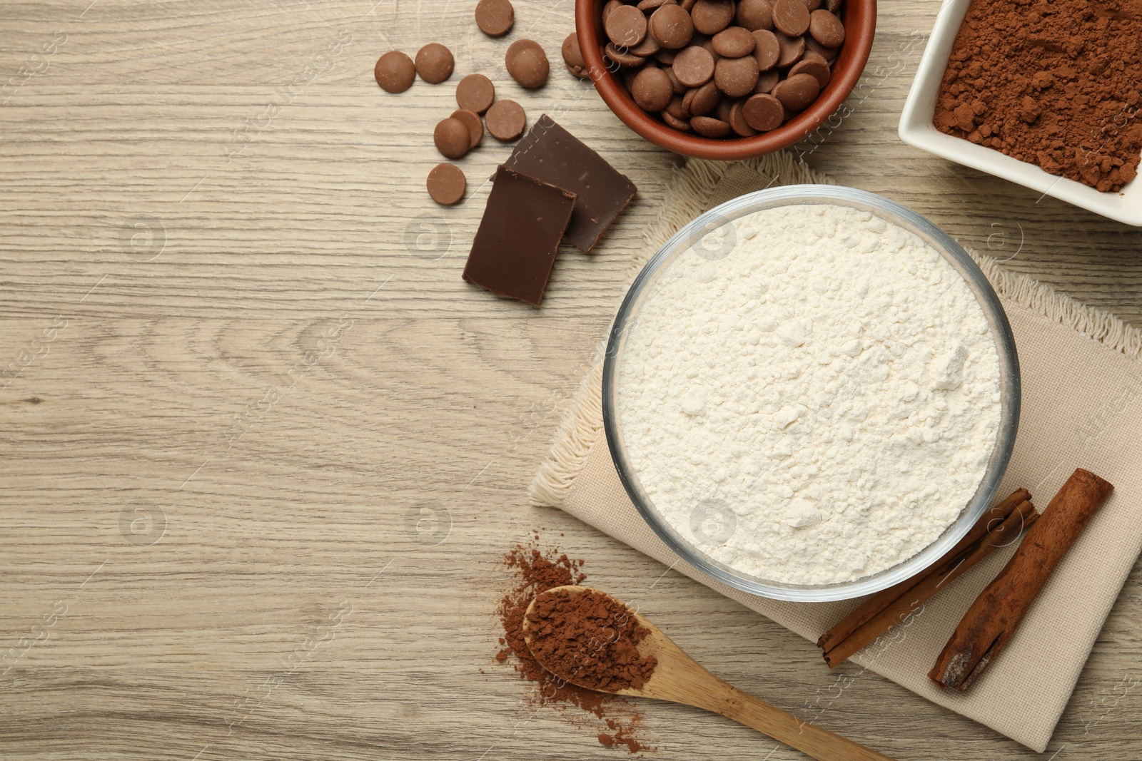 Photo of Flour, chocolate and cocoa for making dough on wooden table, flat lay. Space for text