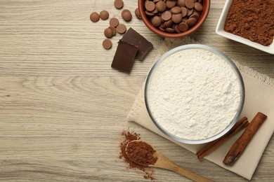 Photo of Flour, chocolate and cocoa for making dough on wooden table, flat lay. Space for text