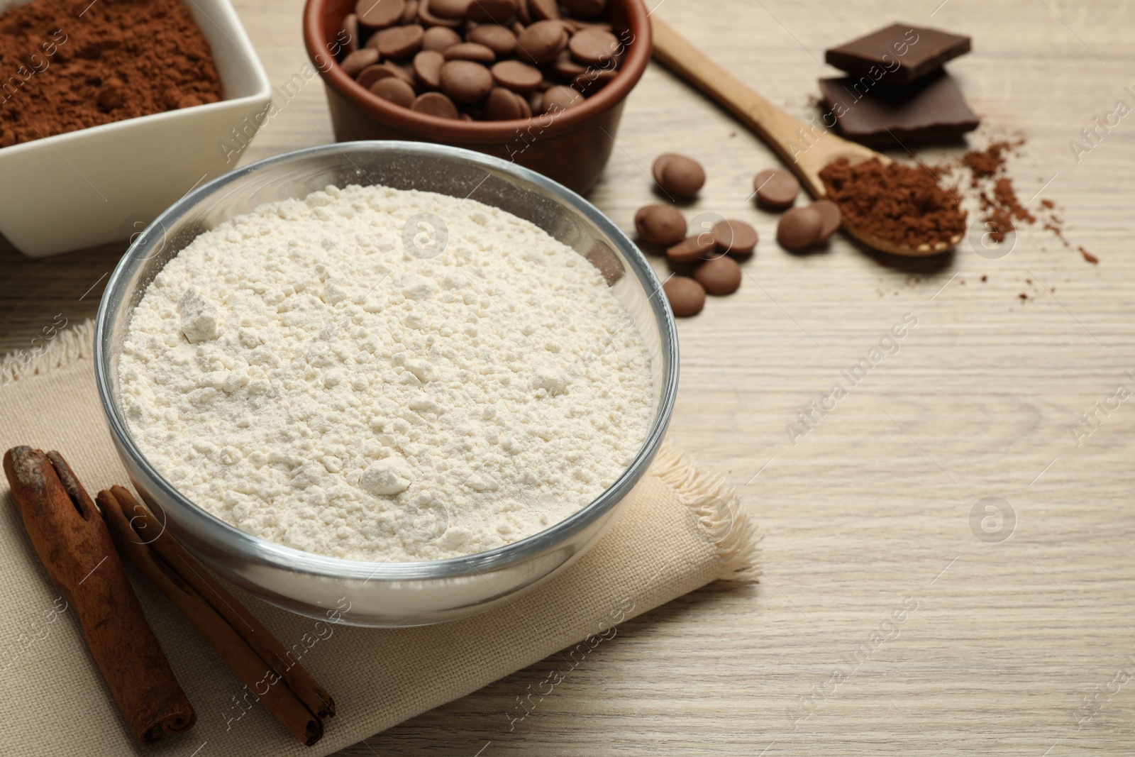 Photo of Flour, chocolate and cocoa for making dough on wooden table, closeup