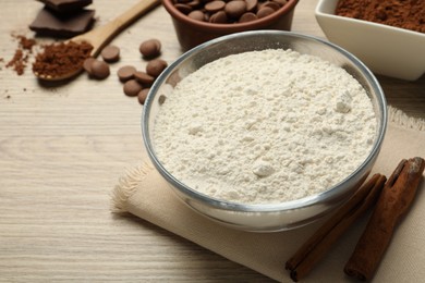 Photo of Flour, chocolate and cocoa for making dough on wooden table, closeup