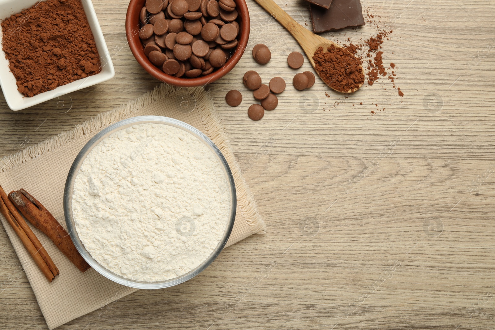 Photo of Flour, chocolate and cocoa for making dough on wooden table, flat lay. Space for text