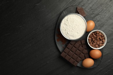 Photo of Flour, chocolate and eggs for making dough on dark textured table, top view. Space for text