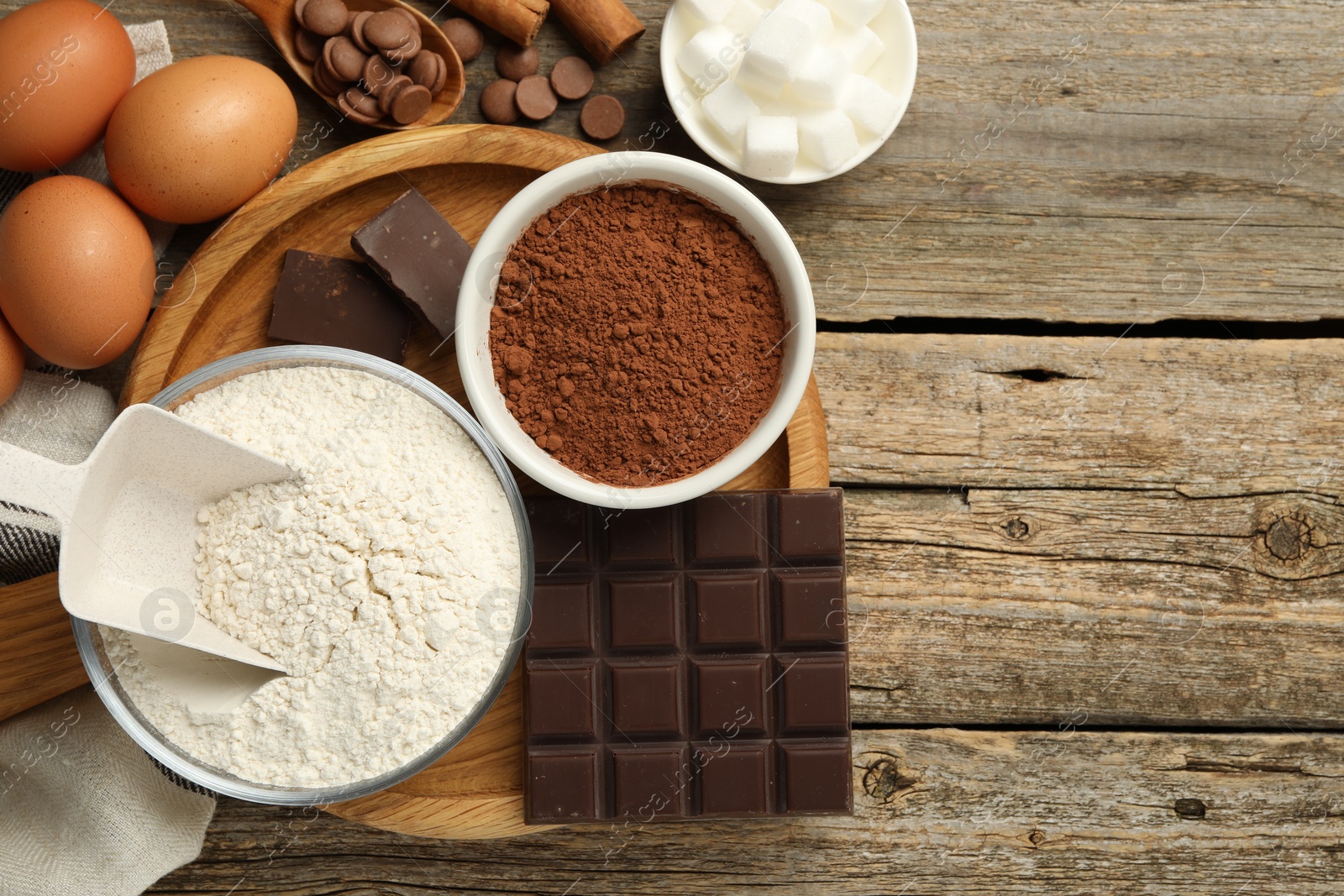 Photo of Flat lay composition with flour, chocolate and other ingredients for making dough on wooden table. Space for text