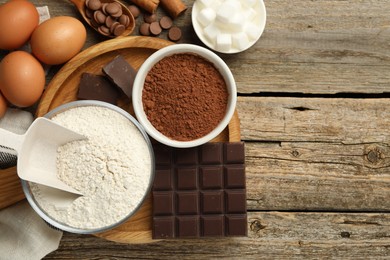 Photo of Flat lay composition with flour, chocolate and other ingredients for making dough on wooden table. Space for text