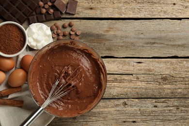 Photo of Chocolate dough in bowl and ingredients on wooden table, flat lay. Space for text