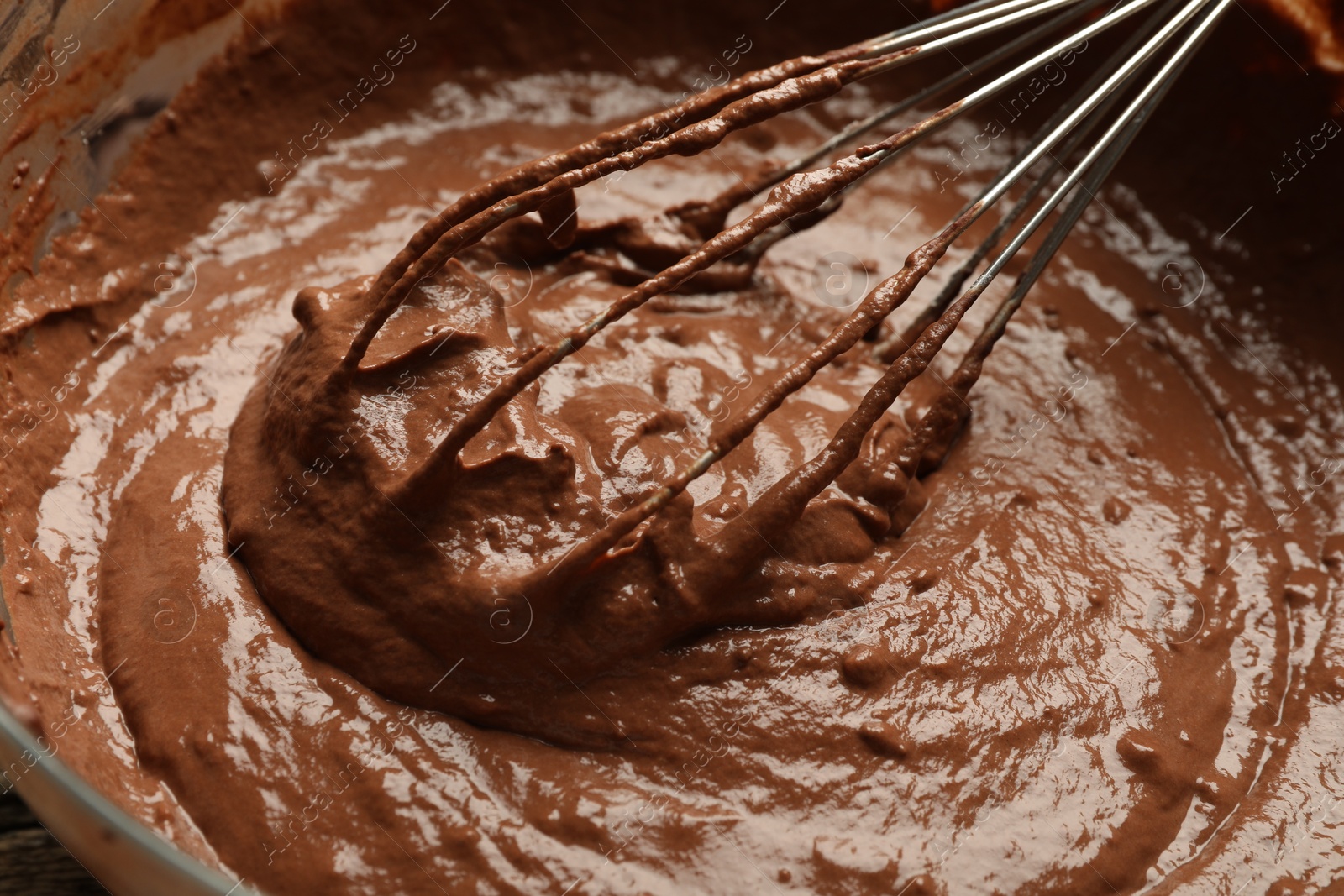 Photo of Chocolate dough and whisk in bowl, closeup