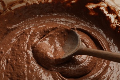 Photo of Chocolate dough and spoon in bowl, closeup