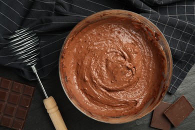 Photo of Chocolate dough in bowl and whisk on dark table, flat lay