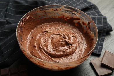 Photo of Chocolate dough in bowl and whisk on dark table, closeup