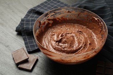 Photo of Chocolate dough in bowl and whisk on dark table, closeup