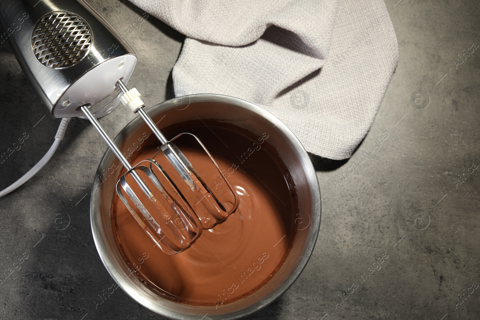 Photo of Chocolate dough in bowl and mixer on grey table, top view