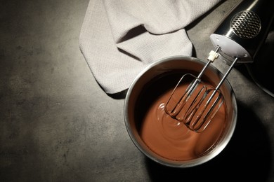 Photo of Chocolate dough in bowl and mixer on grey table, top view. Space for text