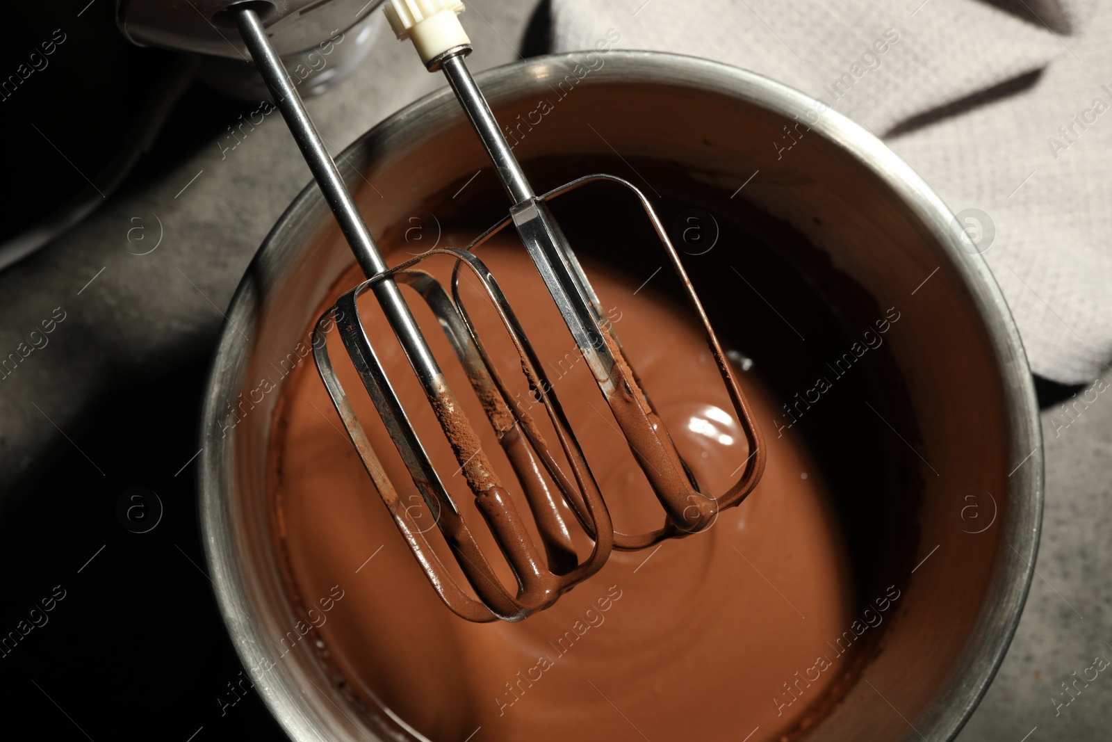 Photo of Chocolate dough in bowl and mixer on grey table, top view