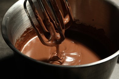 Photo of Chocolate dough dripping from mixer into bowl, closeup