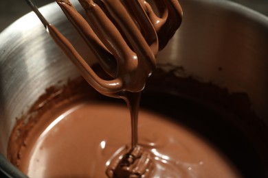 Photo of Chocolate dough dripping from mixer into bowl, closeup