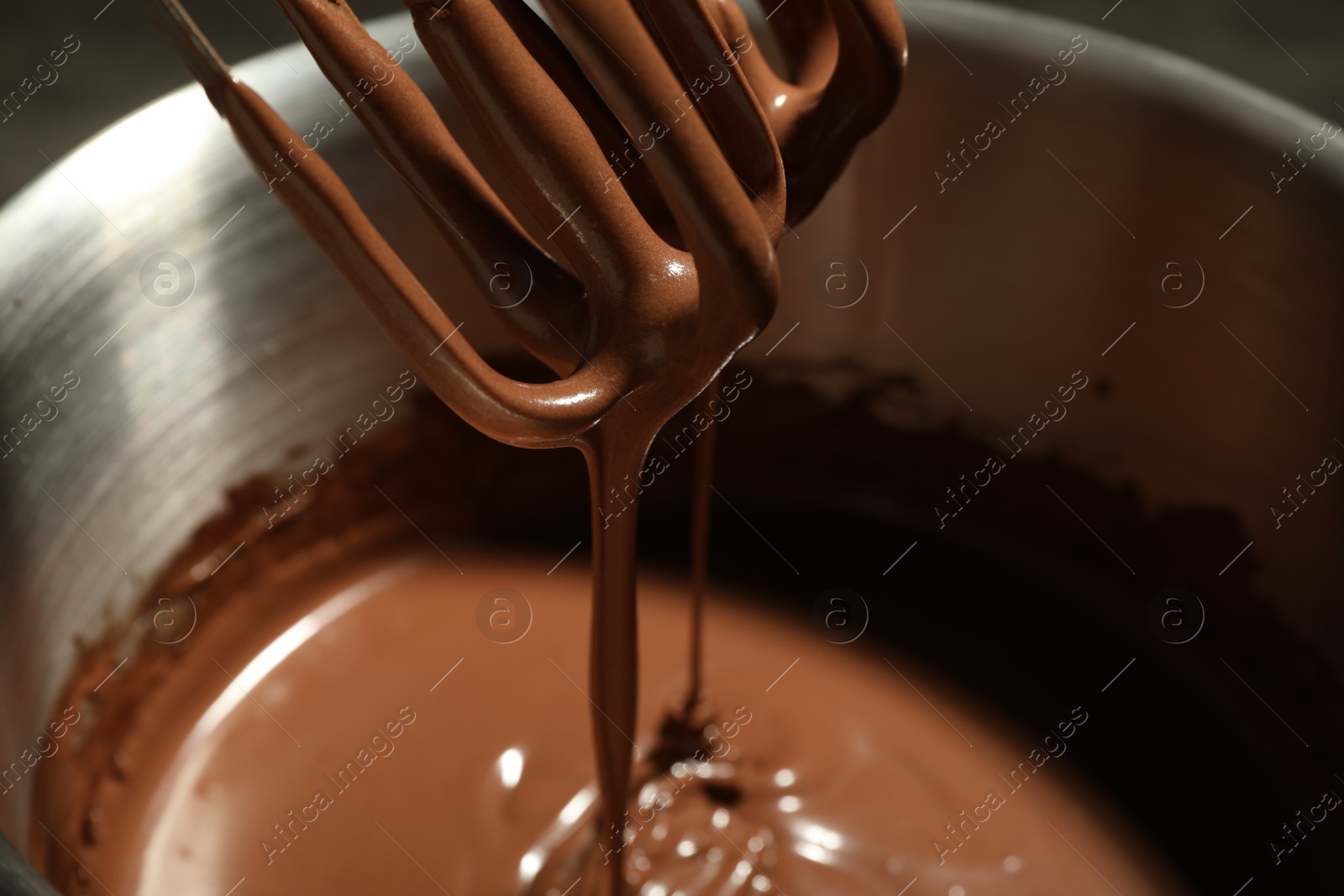 Photo of Chocolate dough dripping from mixer into bowl, closeup