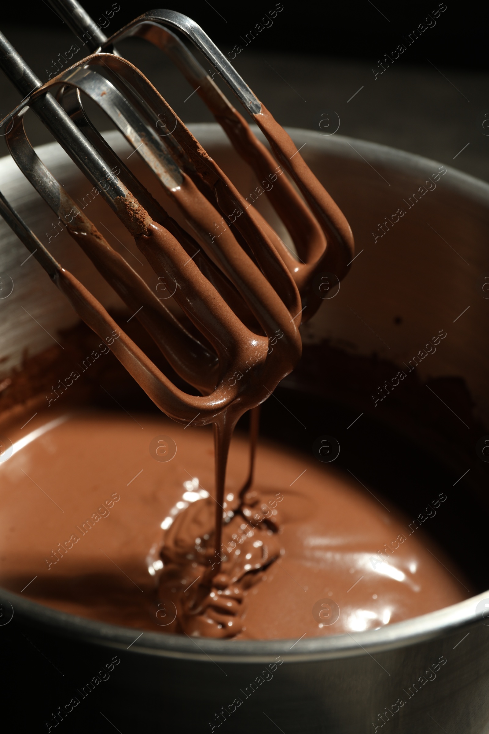 Photo of Chocolate dough dripping from mixer into bowl, closeup