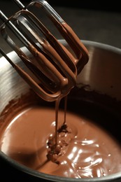 Photo of Chocolate dough dripping from mixer into bowl, closeup