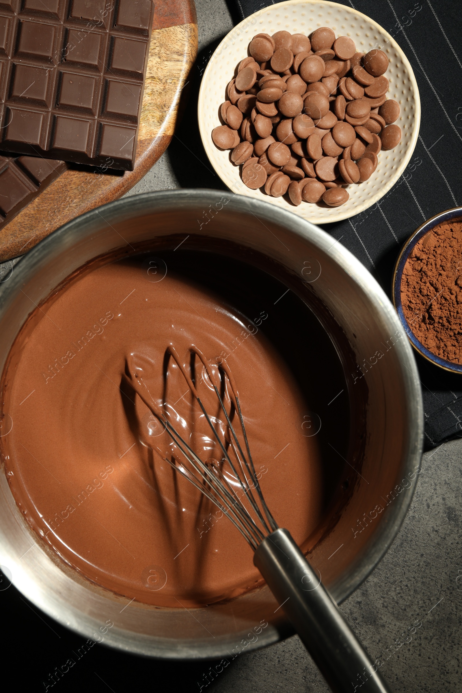 Photo of Chocolate dough in bowl and ingredients on grey table, flat lay