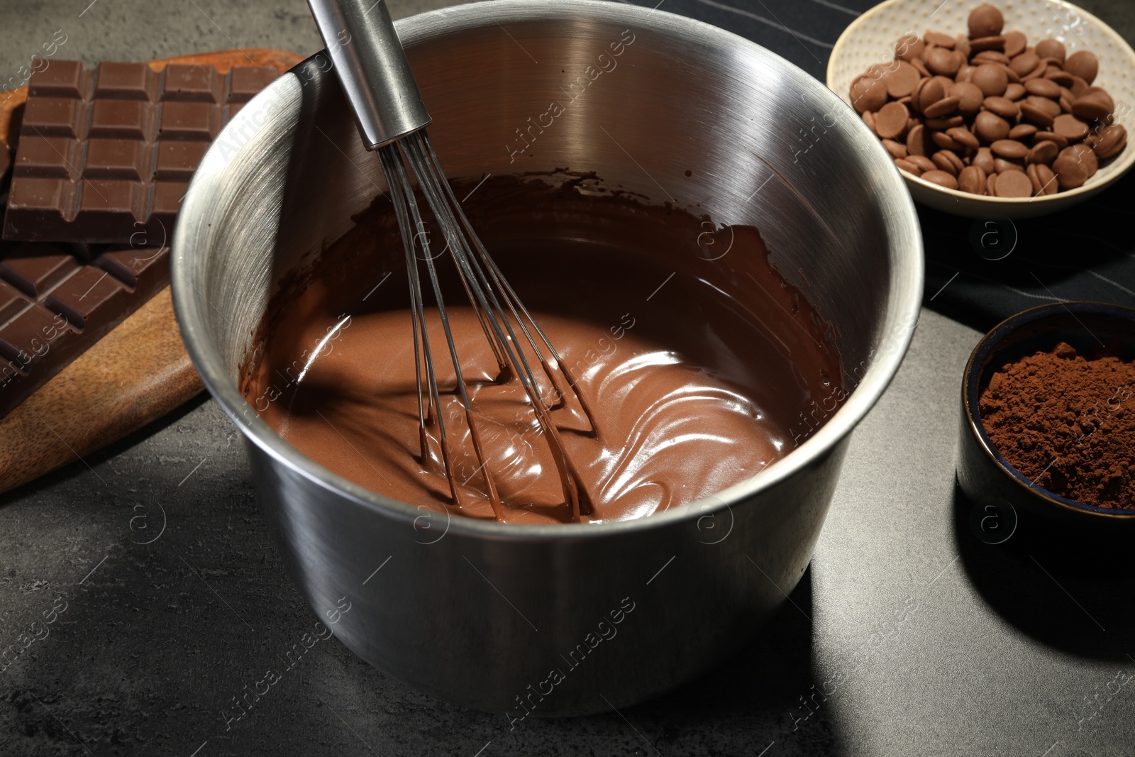 Photo of Chocolate dough in bowl and ingredients on grey table