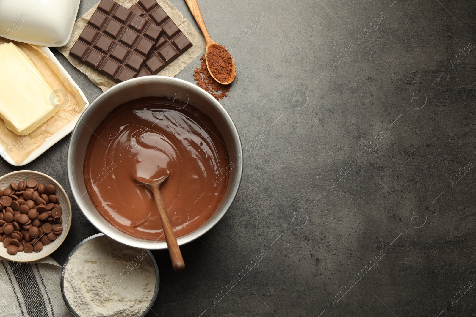 Photo of Chocolate dough in bowl and ingredients on grey table, flat lay. Space for text