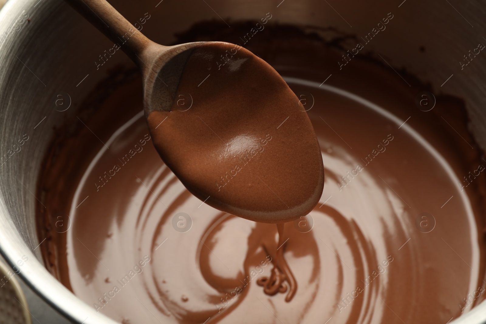 Photo of Chocolate dough dripping from spoon into bowl, closeup