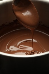 Photo of Chocolate dough dripping from spoon into bowl, closeup