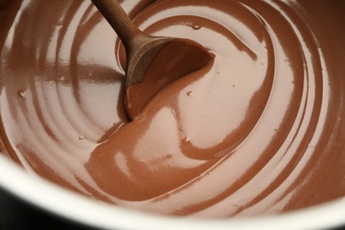 Photo of Chocolate dough and spoon in bowl, closeup