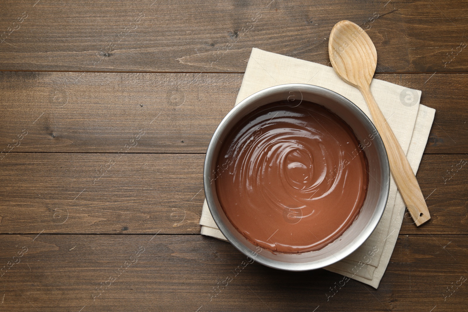 Photo of Chocolate dough in bowl and spoon on wooden table, top view. Space for text